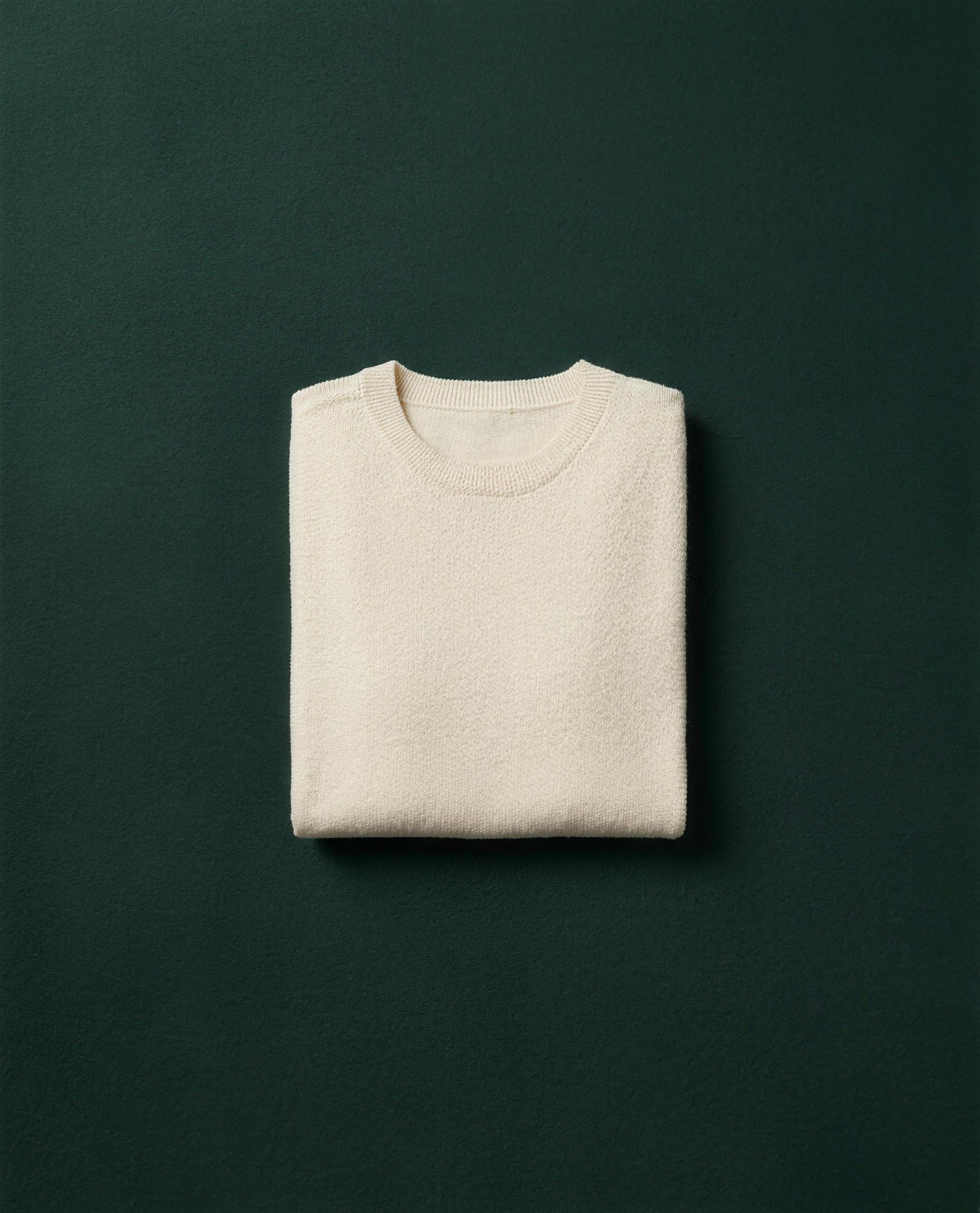 Folded cream cashmere sweater centred on dark green velvet